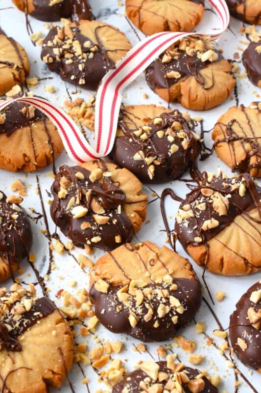 In our home, you cannot go wrong with the classic combination of peanut butter and chocolate! These delicious Chocolate Dipped Peanut Butter Cookies are dipped in melted chocolate and topped with a sprinkling of chopped salted peanuts. These are so easy to make, so whip up several batches and gift them to your friends, neighbours, and coworkers! #peanutbutter #cookies #chocolate #christmas #holiday #baking