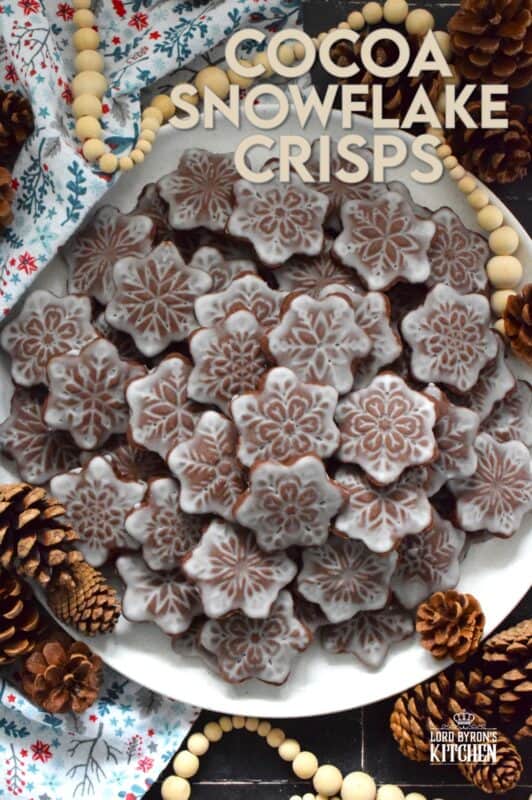 These thin and crispy chocolate cookies are a perfect holiday treat! Cocoa Snowflake Crisps are made with good cocoa and salted butter which help to make them super chocolatey and buttery with a snap-crisp texture. Top them with a thin sugary glaze to make them extra tasty and super festive too! #cocoa #chocolate #snowflake #cookies