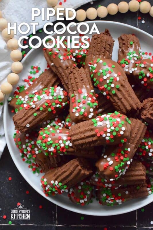 Buttery and chocolatey, Piped Hot Cocoa Cookies are delicious just as they are, but they're even better dipped in silky smooth melted milk chocolate! Not only are these fun to make, but everyone loves them! Be sure to include these tasty little treats on your holiday dessert table this year! #chocolate #cocoa #hotcocoa #cookies