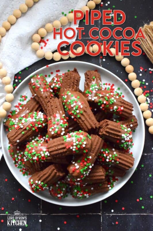 Buttery and chocolatey, Piped Hot Cocoa Cookies are delicious just as they are, but they're even better dipped in silky smooth melted milk chocolate! Not only are these fun to make, but everyone loves them! Be sure to include these tasty little treats on your holiday dessert table this year! #chocolate #cocoa #hotcocoa #cookies