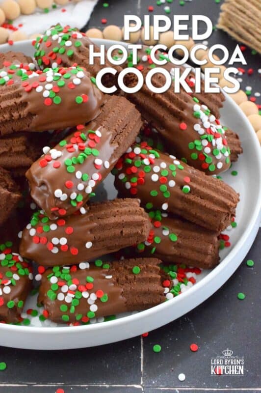 Buttery and chocolatey, Piped Hot Cocoa Cookies are delicious just as they are, but they're even better dipped in silky smooth melted milk chocolate! Not only are these fun to make, but everyone loves them! Be sure to include these tasty little treats on your holiday dessert table this year! #chocolate #cocoa #hotcocoa #cookies