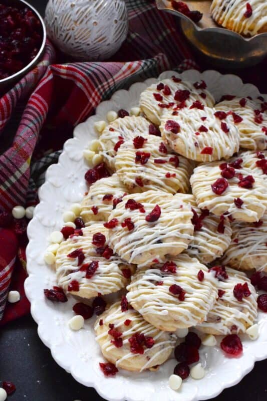 Cranberry White Chocolate Cookies are a simplified version of the seasonally popular bliss bar at Starbucks. Prepared with a light sugar cookie base which is packed with dried cranberries and white chocolate chips, these cookies are topped with a drizzle of white chocolate and even more dried cranberries. #cranberry #chocolate #cookies