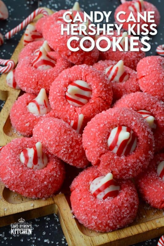 A deliciously decadent peppermint cookie, coated in sugar, and topped with a Hershey's white chocolate kiss, Candy Cane Hershey Kiss Cookies are a perfect holiday treat that everyone will love! These are quick and easy – no need to chill the cookie dough before baking either! Don't they look absolutely adorable!? #thumbprint #hershey #kisses #candycane