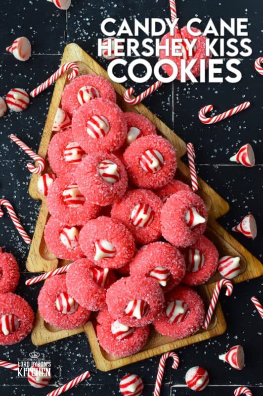 A deliciously decadent peppermint cookie, coated in sugar, and topped with a Hershey's white chocolate kiss, Candy Cane Hershey Kiss Cookies are a perfect holiday treat that everyone will love! These are quick and easy – no need to chill the cookie dough before baking either! Don't they look absolutely adorable!? #thumbprint #hershey #kisses #candycane