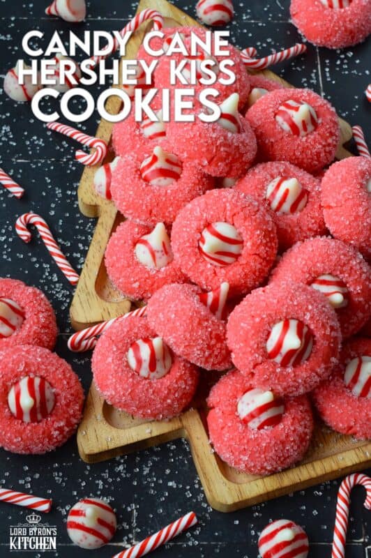 A deliciously decadent peppermint cookie, coated in sugar, and topped with a Hershey's white chocolate kiss, Candy Cane Hershey Kiss Cookies are a perfect holiday treat that everyone will love! These are quick and easy – no need to chill the cookie dough before baking either! Don't they look absolutely adorable!? #thumbprint #hershey #kisses #candycane