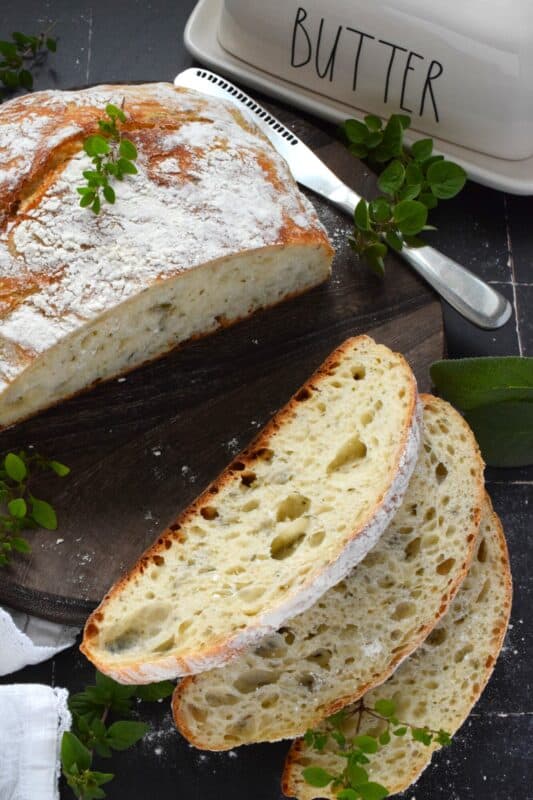 Freshly baked homemade bread is the ultimate comfort food.  There really is nothing like it!  Artisan Garlic and Herb Bread is one of the most delicious and easiest breads you’ll ever make! Loaded with fresh chopped garlic and herbs, this bread is quite aromatic and very savoury! #bread #noknead #dutchoven #homemade #garlic #herbs