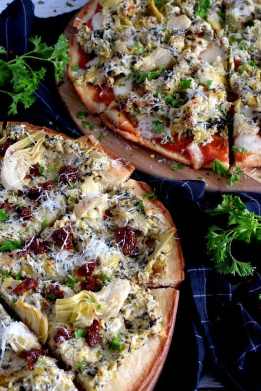 Artichoke and Spinach Dip is an extremely popular appetizer served at many family-style restaurants. But, why not make that delicious dip into a meal with an easy-to-make Artichoke and Spinach Dip Pizza!? Top with sun dried tomatoes and fresh parmesan for even more flavour! #artichokes #spinach #pizza #dip #sundried #tomatoes
