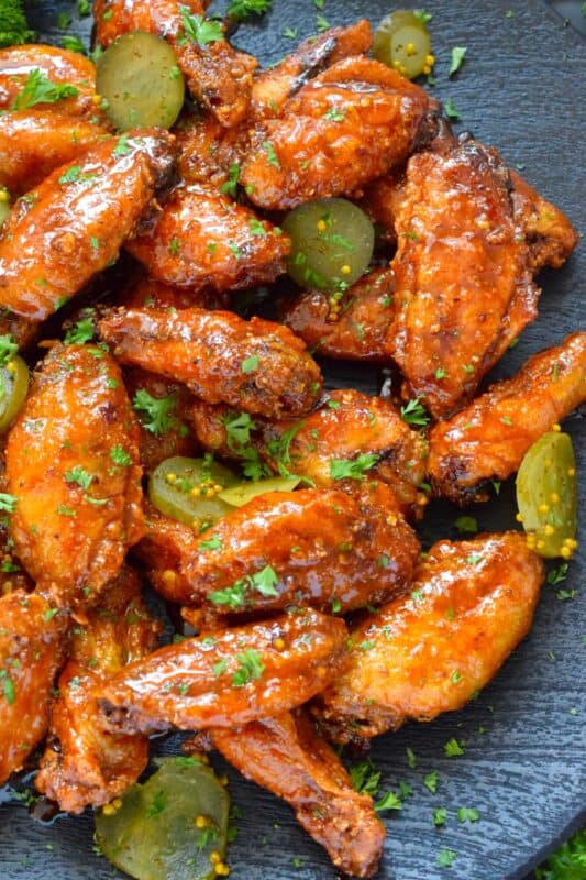 Baked to perfection with a crispy coating and a tender and juicy interior, these wings are drenched in a hot sauce comprised of cayenne, chili, garlic, onion, and melted butter, Baked Nashville Hot Wings also have an optionally sweet honey component! Plate these wings with sweet pickle slices for a cooling crunch! #baked #nashville #hot #chicken #wings #sticky