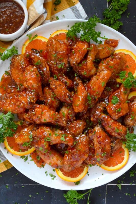 These very sticky wings are prepared with orange marmalade preserves, barbecue sauce, hot sauce, chilies, and seasonings. Orange Chicken Wings are the stickiest and most delicious wings you'll ever eat! They are baked until crispy on the outside and tossed in one of the quickest and easiest sauces! These wings don't need a special occasion; serve these any time you feel like it! #orange #wings #chicken #bbq #sauce #hotsauce