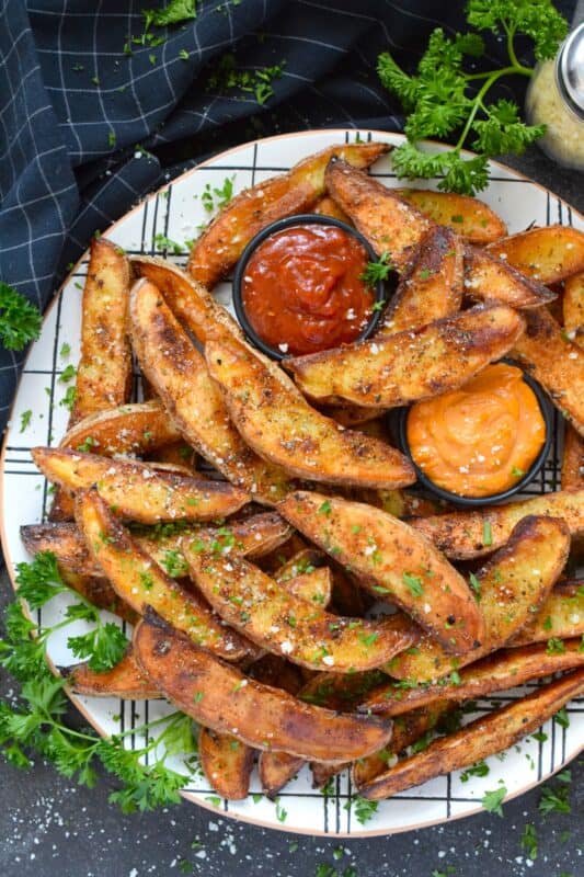 Baked with a light, pillowy center and a crispy crust, Pizza Potato Wedges are seasoned and flavoured with oregano, basil, garlic, onion, and parmesan, making them the perfect pairing with homemade pizza and chicken wings too! #pizza #potato #wedges #sides #seasoned