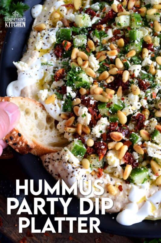 What's a party without dip? Hummus Party Dip Platter is a large, layered dip that's just perfect for entertaining a crowd. This all-in-one dip has hummus, sour cream, pine nuts, sun dried tomatoes, cucumbers, feta, and a few other ingredients too! Serve this on any occasion for a delicious, crowd-pleasing appetizer! #hummus #dip #appetizer #party #platter #spread