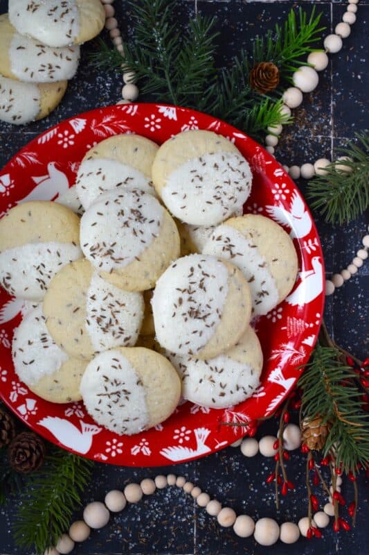 These tender, soft, and moist Caraway Christmas Cookies are prepared with a basic vanilla and caraway seed-flavoured cookie dough. Dipped in melted white chocolate and sprinkled with coarse sanding sugar and more caraway, these cookies are a great addition to any holiday cookie exchange or cookie platter! #caraway #cookies #chocolate #christmas