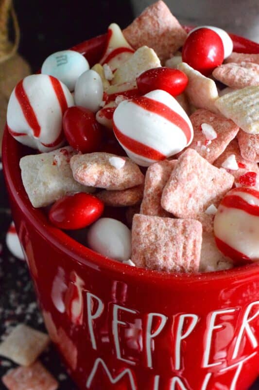 Assemble a big batch of these Candy Cane Muddy Buddies and package them up for your workmates, friends, and neighbours. Loaded with peppermint flavour and lots of chocolate, this snack mix will disappear quite quickly! Alternatively, set out a big bowl with cellophane bags and ribbon and encourage friends and guests to help themselves before leaving your holiday party! #candycane #peppermint #muddy #buddies #christmas #gift