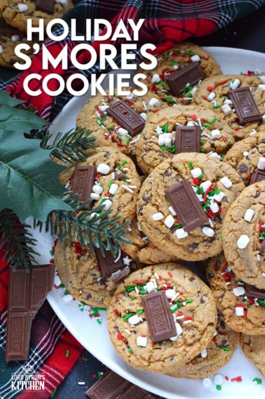 As the name implies, Holiday S'mores Cookies are prepared to resemble the flavour of everyone's favourite backyard fire treat! Baked with graham crumbs, chocolate, and brown sugar, these are a soft-baked cookie with a crispy edge. The texture of the crumbs with the milk chocolate is sensational. Topped with a bar of Hershey's chocolate, these cookies are a must this holiday season! #holiday #smores #cookies #christmas #baking