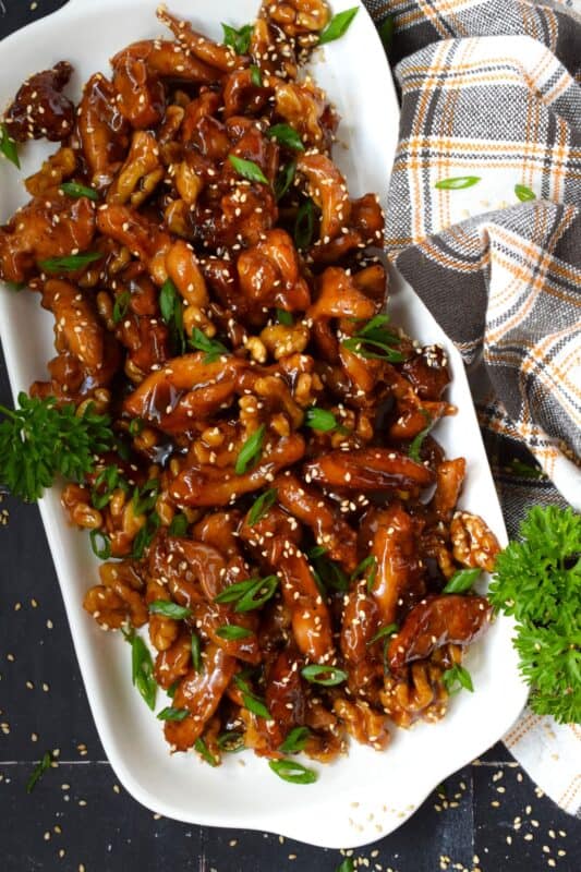 Quite a popular dish at almost every North American Chinese buffet, Crispy Walnut Chicken is prepared with moist and tender boneless and skinless chicken thighs. The chicken is coated and fried until crispy then tossed in a sweet sauce made with honey, soy, sesame, and of course, walnuts! #friedchicken #chicken #sweet #soy #walnut