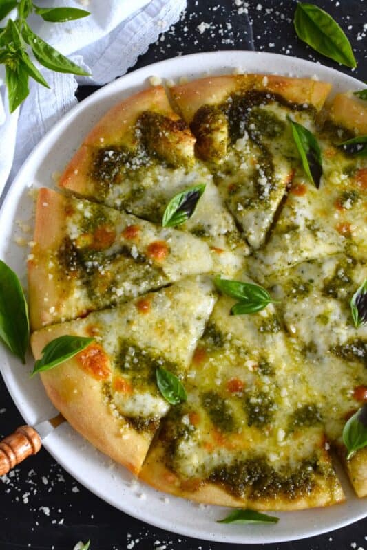 There is no steadfast rule that states pizza must be prepared with tomato sauce and the proof can be found right here in this Pesto and Cheese Pizza recipe! Start with a quick and easy homemade pesto sauce and a very simple pizza dough - you can use store-bought pesto and dough too! Either way, this pizza is bound to impress! #pizza #pesto #basil #vegetarian #cheese
