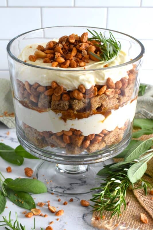 Starting with a homemade eggnog-infused, holiday rum cake, this Spiced Eggnog Trifle is layered with an eggnog cream cheese rum filling and candied mixed nuts.  Drizzled with a thick, sweet caramel sauce, this trifle is sure to be a hit!  Optionally, this recipe easily converts to a rum-free version too! #trifle #spiced #eggnog #cake #caramel #nuts