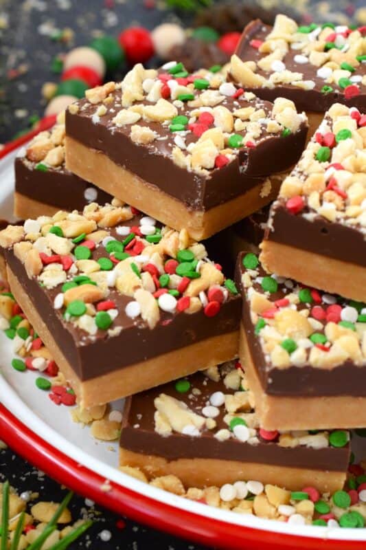 Peanut Butter Squares are a twist on the classic Peanut Butter Ball recipe. These are less time-consuming for sure but are prepared with the smooth peanut butter lover in mind. It's the same great taste but without the crunch of the rice cereal! Christmas cookie boxes are nothing without these delicious confections! #peanutbutter #christmas #squares #nobake