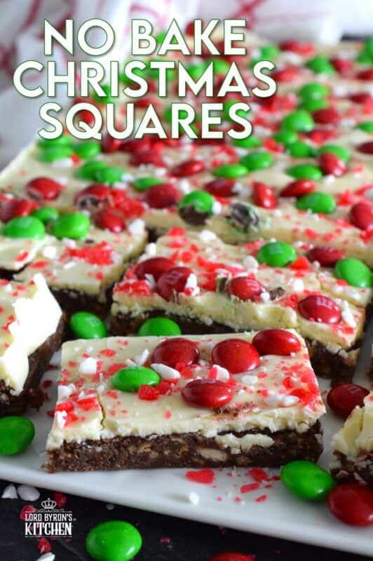 No Bake Christmas Squares have a rich, chocolatey base prepared with crushed cookies, cocoa, and brown sugar. They are topped with melted white chocolate, crushed candy canes, and holiday M&Ms. Only 25 minutes from start to finish! #mms #nobake #christmas #peppermint #cookies #bars #squares