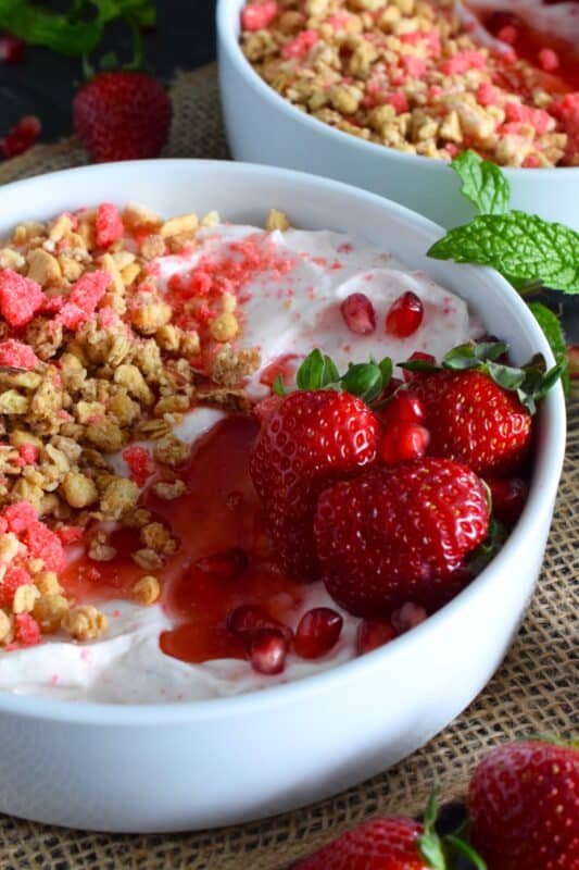 Strawberry shortcake crumbs are stirred into Greek yogurt and then topped with fresh strawberries, more shortcake crumbs, a drizzle of homemade quick and easy strawberry syrup, and a little granola for added crunch and flavour. Strawberry Shortcake Yogurt Bowls make a great summer Sunday brunch menu option! #strawberry #shortcake #crumbs #yogurt #bowls #brunch #summer