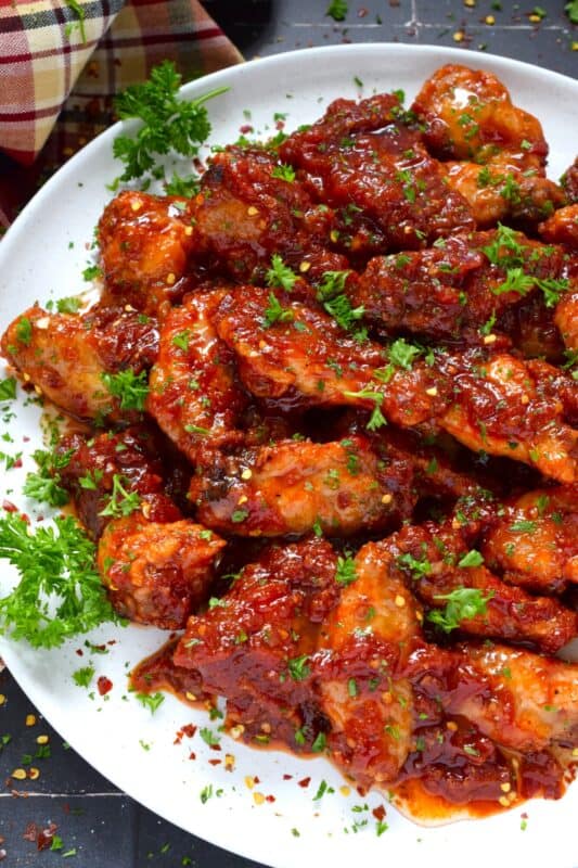 If wings dripping with a spicy and savoury sauce are what you're looking for, you've found them! Atomic Chicken Wings are baked until crispy and then tossed in a homemade sweet and spicy sauce made with crushed tomatoes, hot sauce, brown sugar, and lots of aromatic seasonings. You've never eaten wings this good! #chicken #wings #saucy #atomic #spicy #sweet #copycat #wingstop