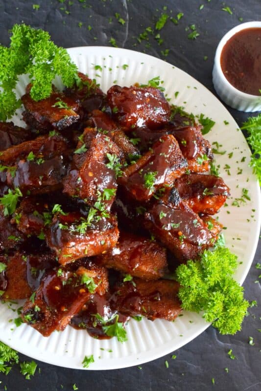 Moist and tender, these pork ribs are enclosed and baked to lock in flavour and texture before they are basted in a deliciously savoury and sweet honey barbecue sauce and broiled until slightly charred. Serve these ribs with lots of napkins, because the sauce is sticky and generous! #ribs #porkribs #honey #barbecue #bbq #baked